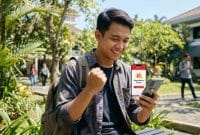 Mahasiswa Indonesia tersenyum senang setelah berhasil mengklaim bonus kuota Telkomsel gratis di smartphon